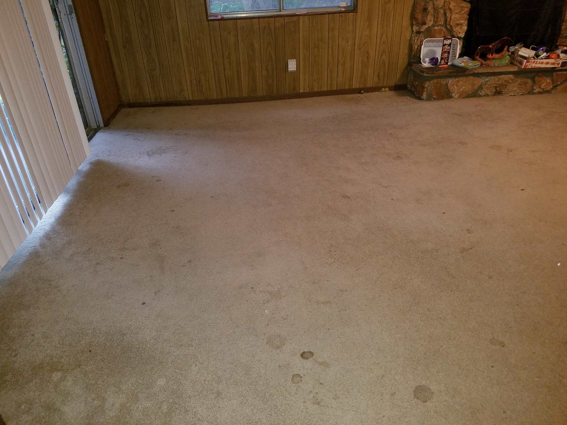 Empty room with beige carpet and wood panel walls.