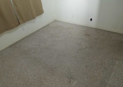 Empty carpeted room with beige curtains.