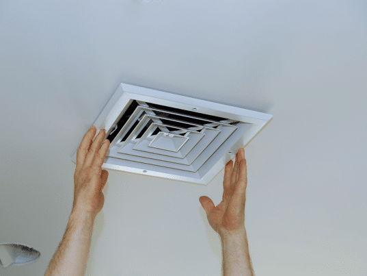 Installing ceiling air vent with hands