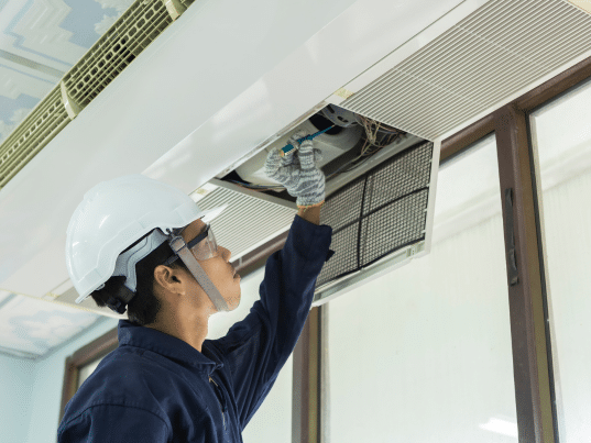 Technician inspecting ceiling air conditioning unit.